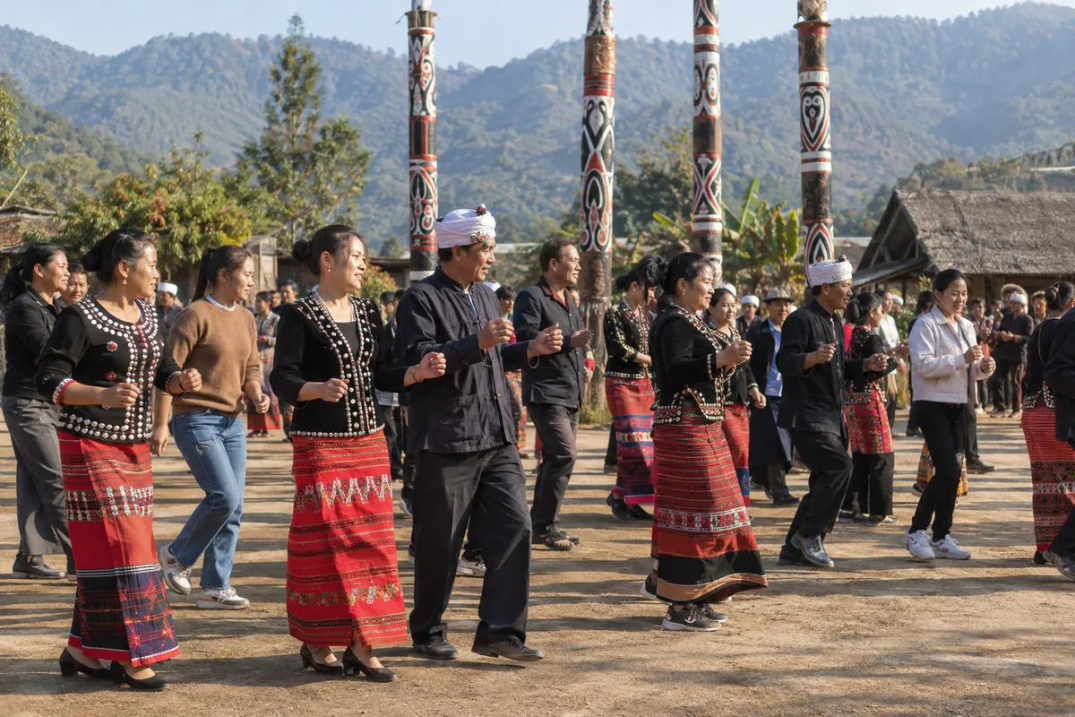 Jingpo-inspired dancers moving together beside decorated posts